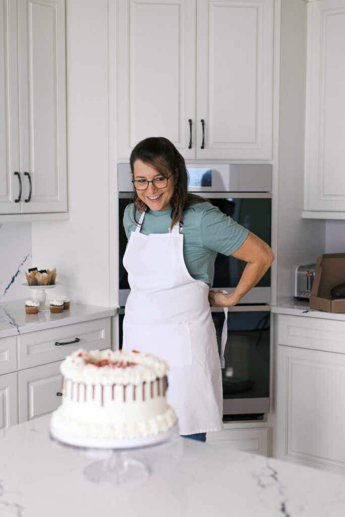 Brunette woman ties a white apron, preparing to bake