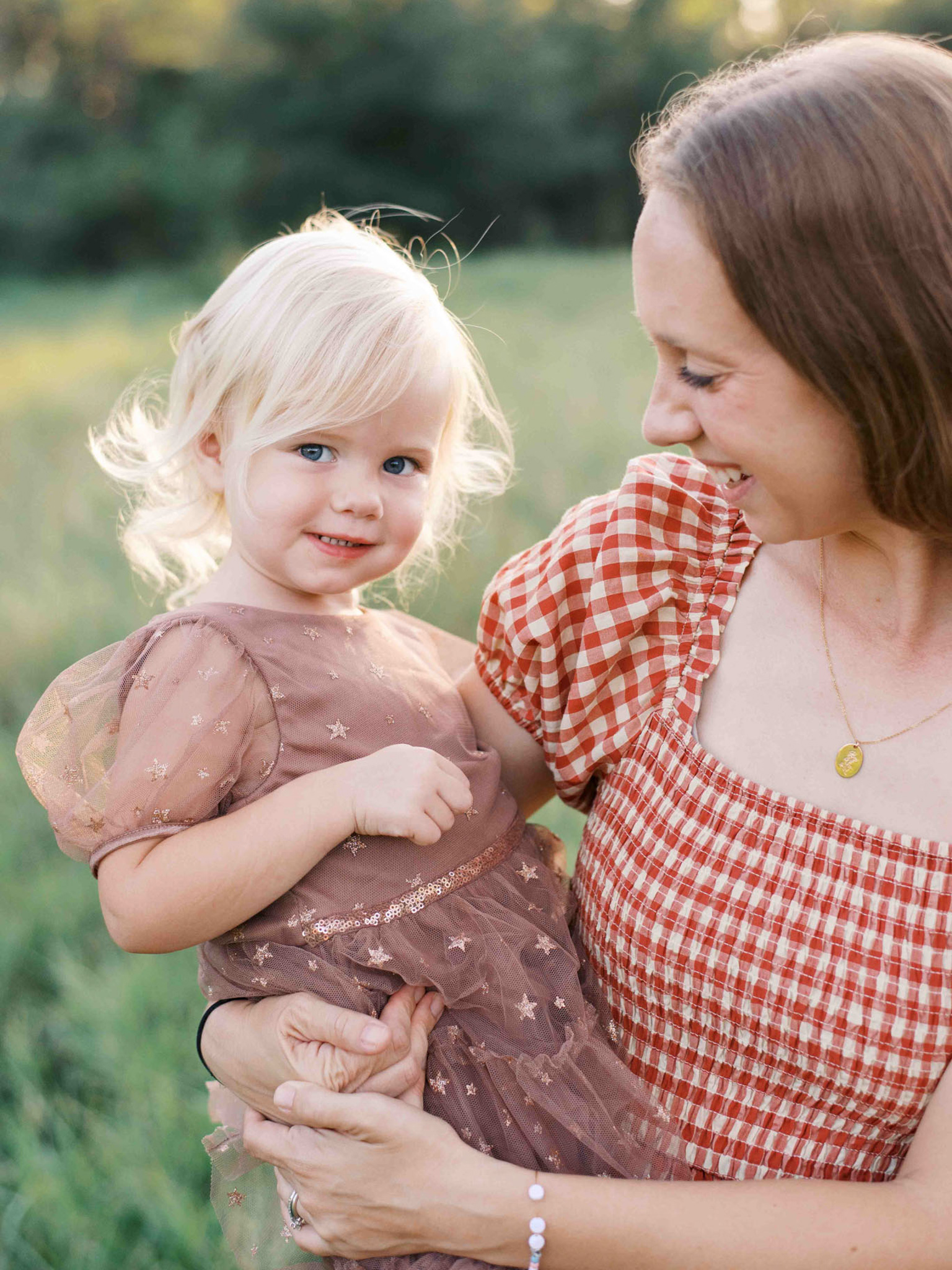 A young mother holds her toddler daughter, who's smiling at the camera