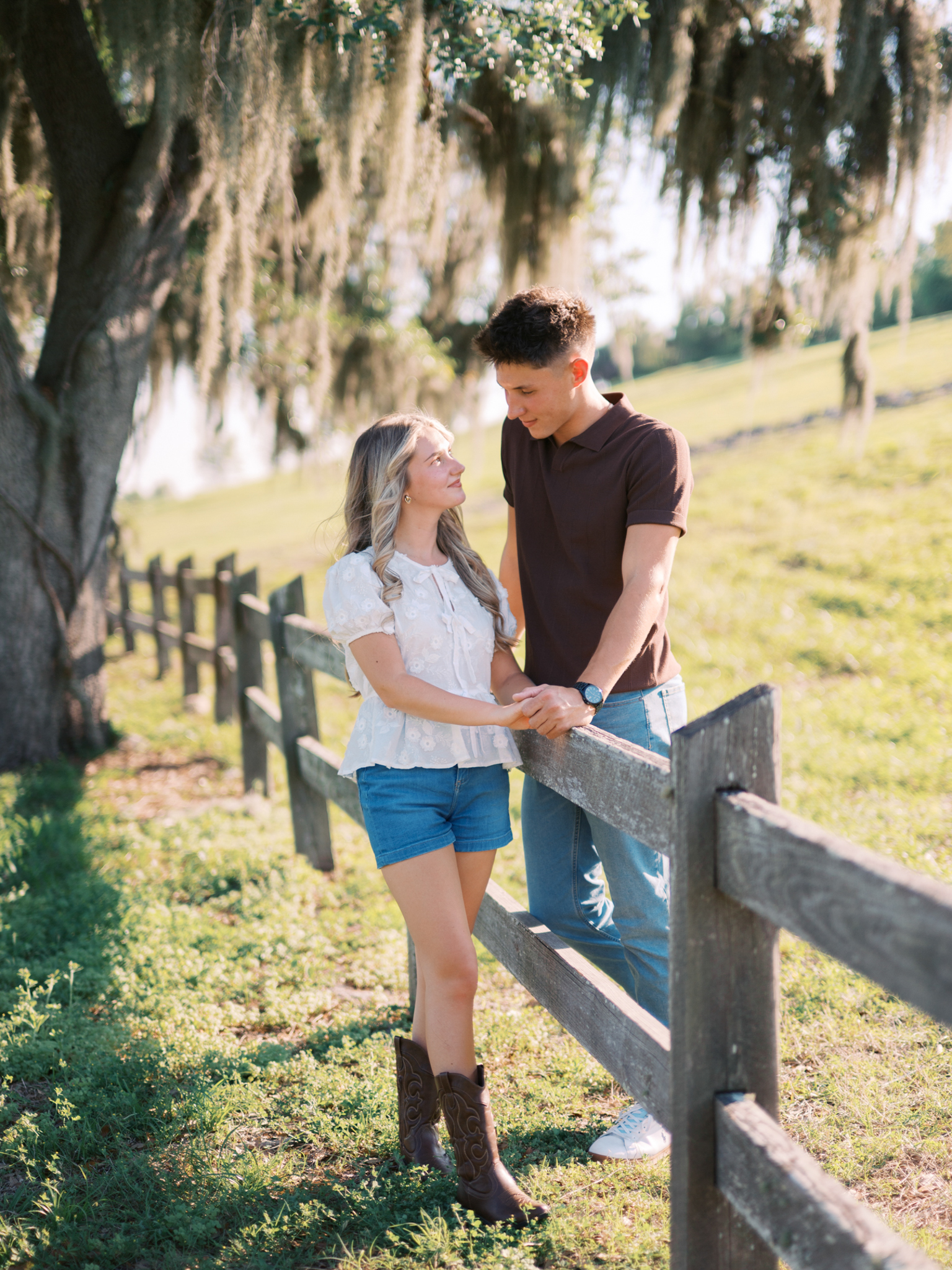 A young couple stands on opposite sides of a fence, looking at each other